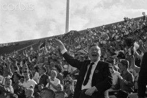 06 Oct 1962, Jackson, Mississippi, USA --- Original caption: 10/6/1962-Jackson, Mississippi- Confederate flags waving behind him, Mississippi Governor Ross Barnett yells along with the rest of the crowd as the Rebels of the University of Mississippi defeat Houston University, in Jackson, by a score of 40-7. This was the Rebels' Homecoming Game, removed from Oxford to Jackson after the riots last weekend over the registration of negro James Meredith at the University. --- Image by © Bettmann/CORBIS